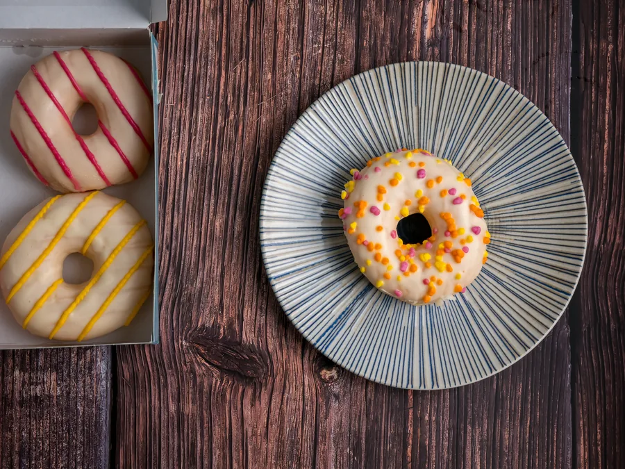 Donut blanco con pequeñas decoraciones rosas, amarillas y naranjas