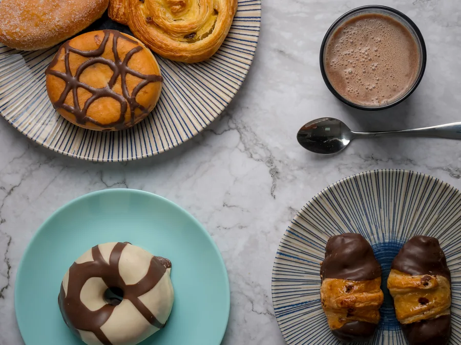 Donuts, hojaldres y cruasanes de chocolate en varios platos sobre mármol