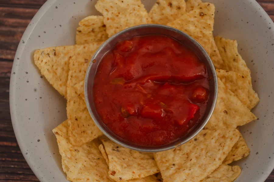 Vista cenital de nachos alrededor de un cuenco de salsa roja