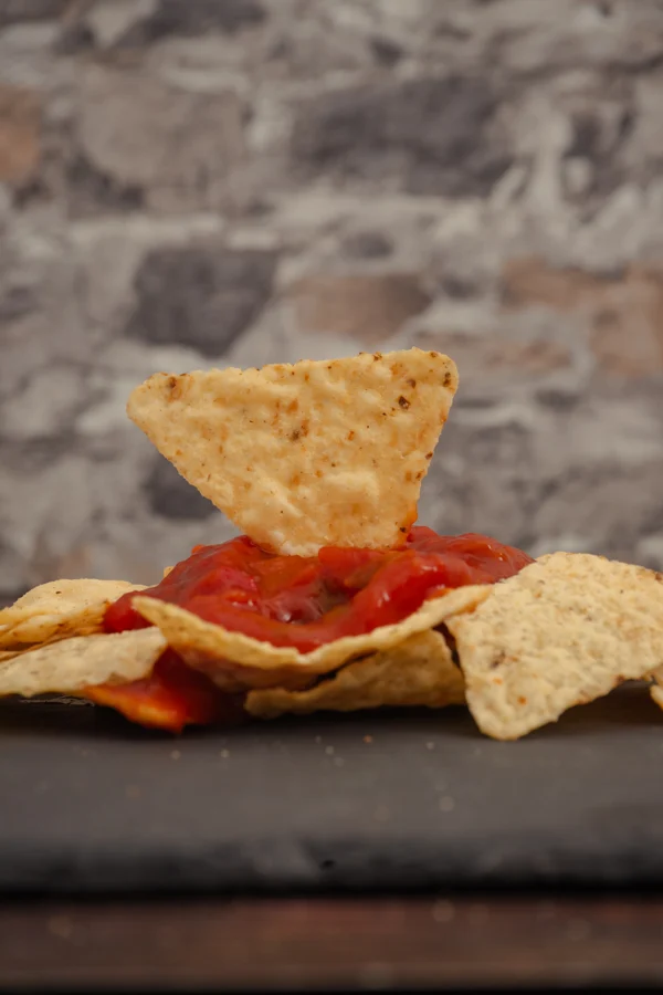 Nacho sobre salsa roja rodeado de otros nachos