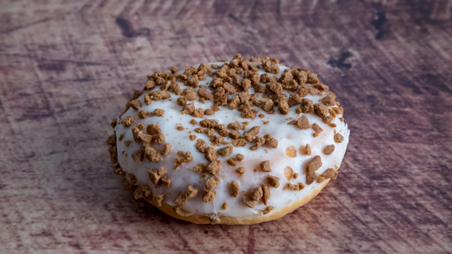 Bollo glaseado con trocitos de galleta sobre madera
