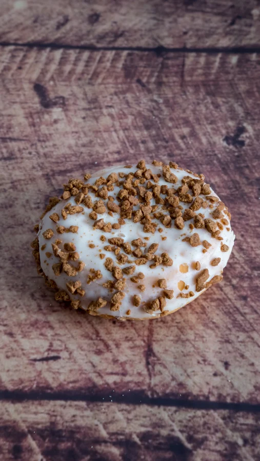 Fotografía vertical de un bollo glaseado con galleta sobre madera