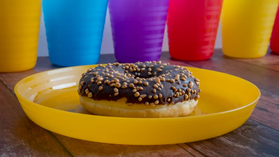 Rosquilla de chocolate con pequeñas bolitas sobre un plato amarillo